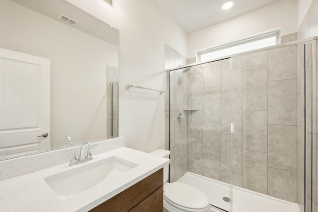 full bathroom featuring toilet, vanity, a shower stall, and visible vents