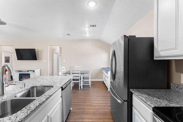 kitchen with appliances with stainless steel finishes, sink, white cabinets, light stone countertops, and lofted ceiling