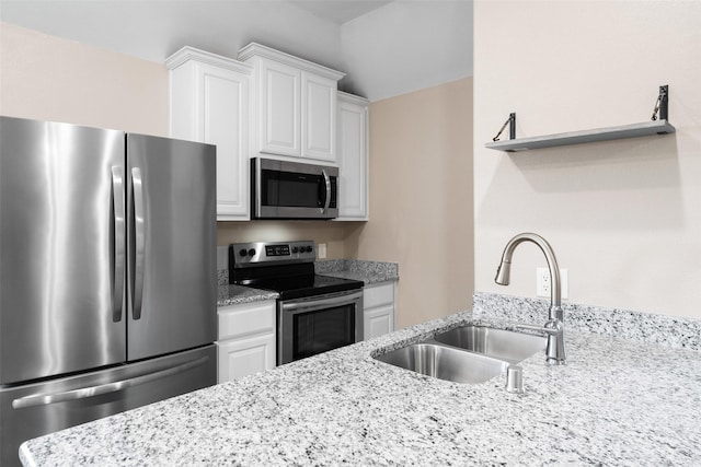 kitchen featuring sink, light stone counters, white cabinets, and appliances with stainless steel finishes