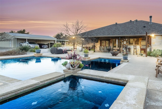 pool at dusk featuring an outdoor living space, a patio, and an outdoor bar