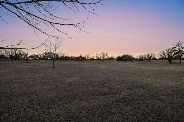 yard at dusk featuring a rural view