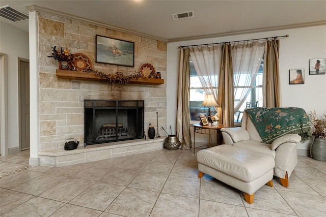 sitting room featuring a stone fireplace, ornamental molding, and tile patterned flooring