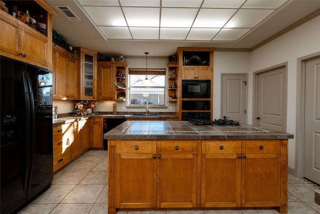 kitchen with a kitchen island, black appliances, decorative light fixtures, and sink