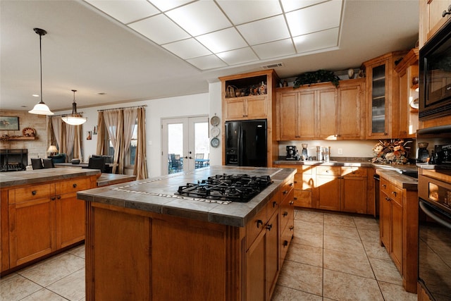 kitchen featuring pendant lighting, french doors, light tile patterned floors, a center island, and black appliances