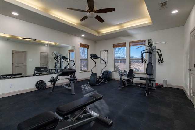 workout area with ceiling fan and a raised ceiling