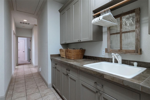 kitchen with sink, light tile patterned floors, and gray cabinetry