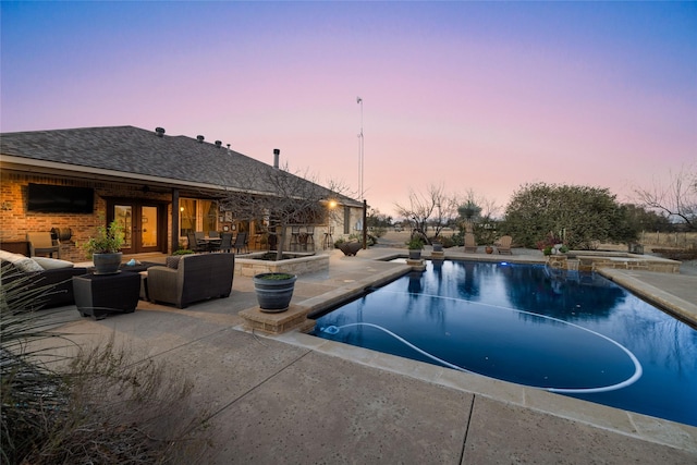 pool at dusk with a patio area, outdoor lounge area, an in ground hot tub, and french doors