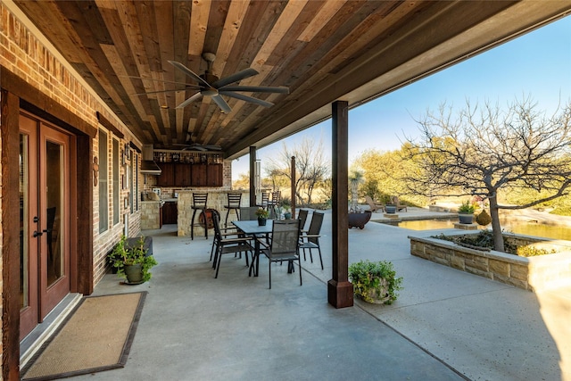 view of patio with ceiling fan and a bar