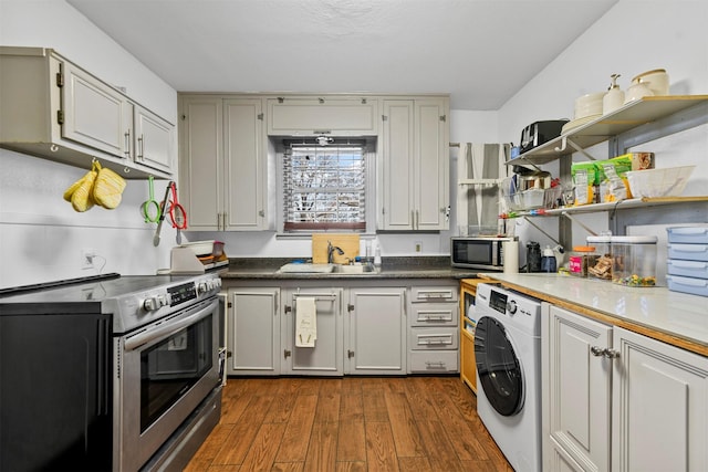 kitchen with sink, washer / dryer, appliances with stainless steel finishes, and dark wood-type flooring