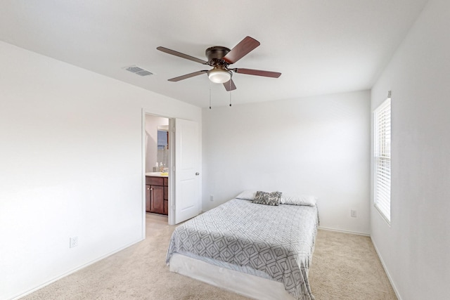 bedroom featuring ceiling fan, ensuite bathroom, and light colored carpet