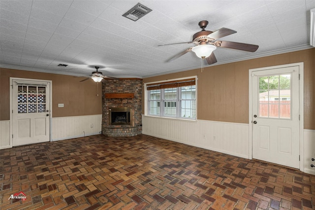 unfurnished living room with ceiling fan, crown molding, and a fireplace