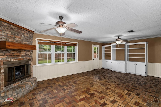 unfurnished living room featuring ceiling fan, a brick fireplace, ornamental molding, and dark parquet flooring