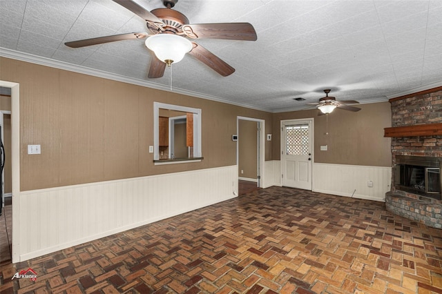 unfurnished living room featuring ceiling fan, crown molding, and a fireplace