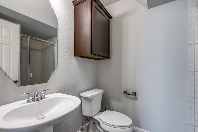 bathroom featuring sink, an enclosed shower, and toilet