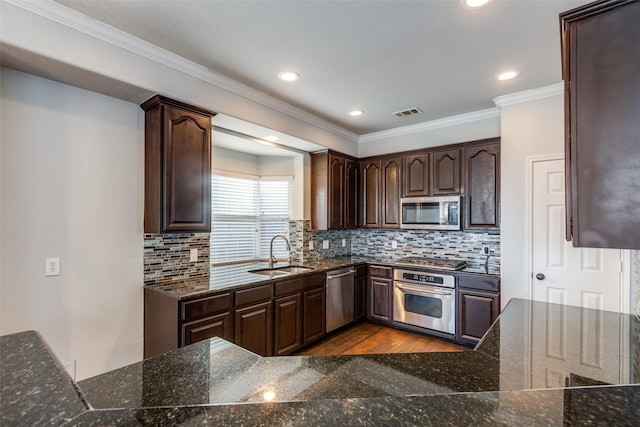 kitchen with dark brown cabinetry, appliances with stainless steel finishes, sink, and backsplash