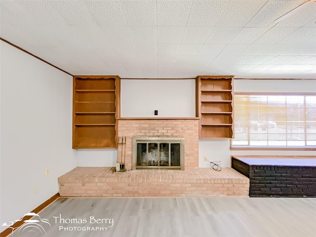 unfurnished living room featuring hardwood / wood-style flooring and a brick fireplace