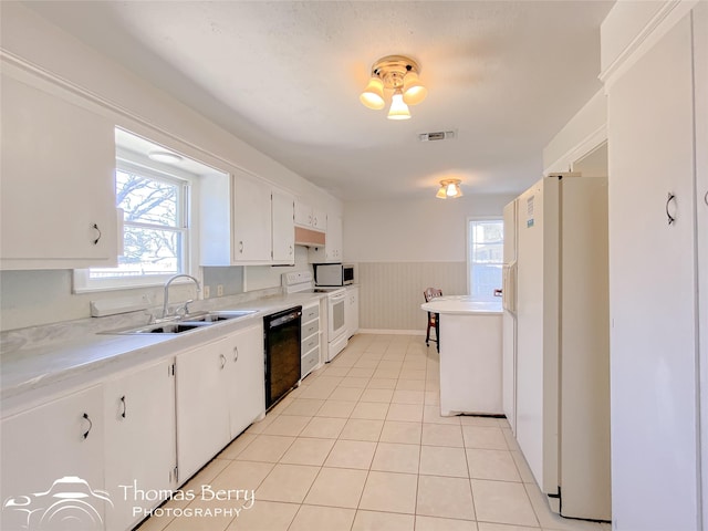 kitchen featuring sink, white appliances, light tile patterned floors, white cabinetry, and wooden walls