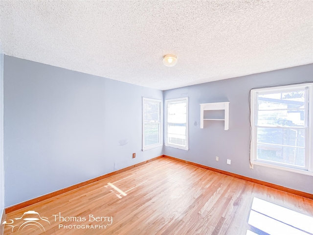 unfurnished room with a textured ceiling and light hardwood / wood-style floors