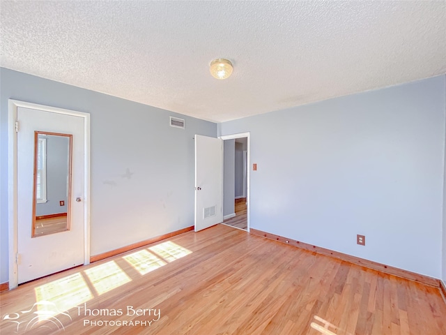 spare room with light hardwood / wood-style floors and a textured ceiling