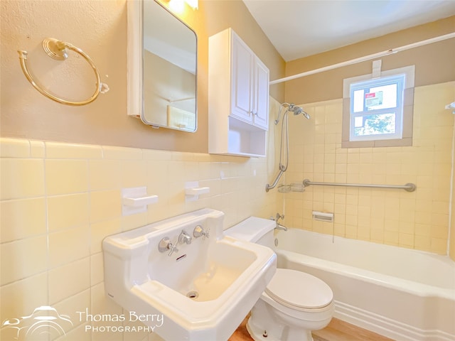 full bathroom with tile walls, sink, tiled shower / bath combo, and toilet