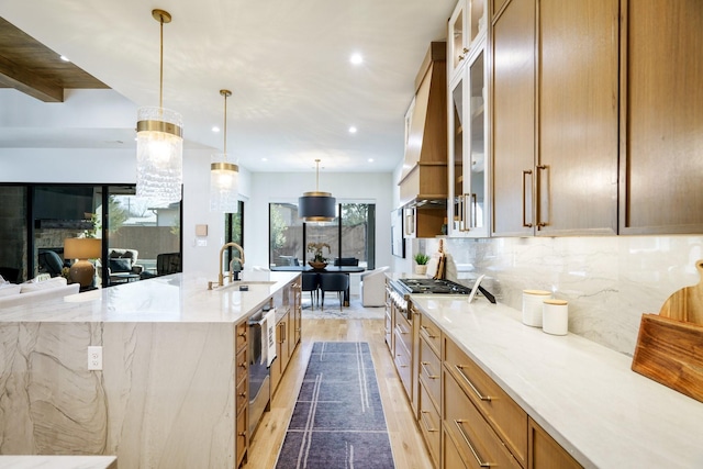 kitchen featuring sink, wood-type flooring, pendant lighting, light stone countertops, and decorative backsplash