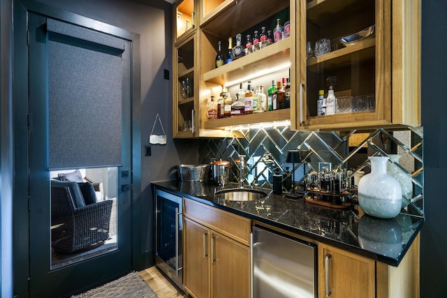 bar featuring tasteful backsplash, dark stone counters, beverage cooler, and sink