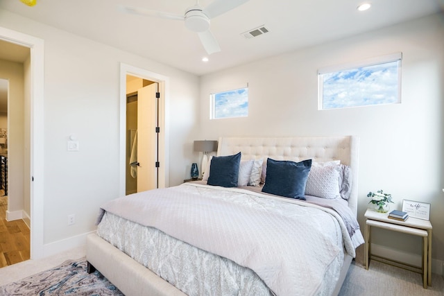 carpeted bedroom featuring multiple windows and ceiling fan