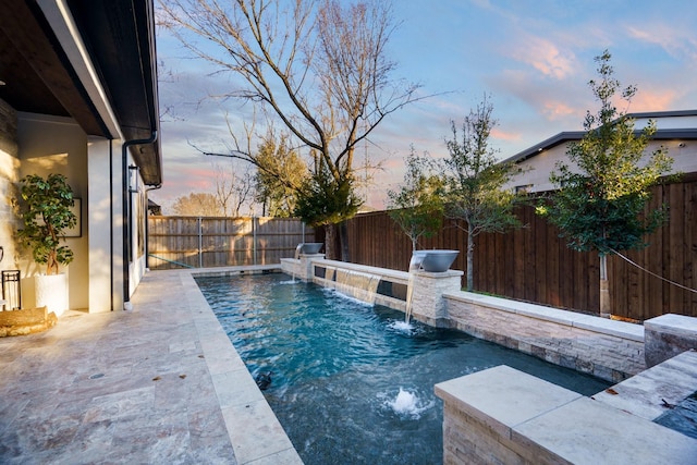 pool at dusk featuring pool water feature