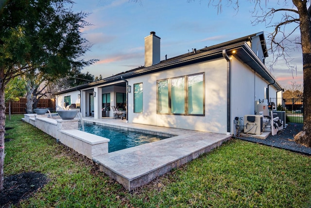 back house at dusk featuring a yard, a fenced in pool, and a patio area