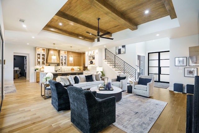 living room featuring beam ceiling, light wood-type flooring, and wood ceiling