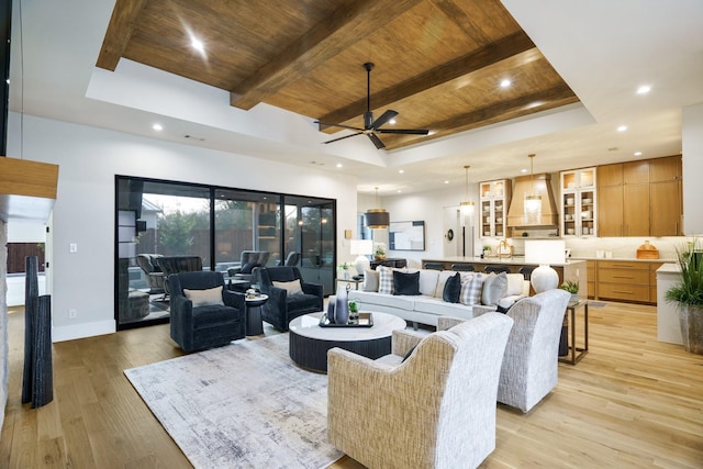 living room with wood ceiling, a tray ceiling, ceiling fan, light wood finished floors, and beam ceiling
