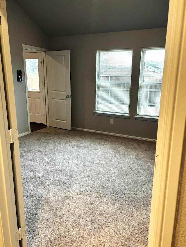 empty room featuring vaulted ceiling and carpet