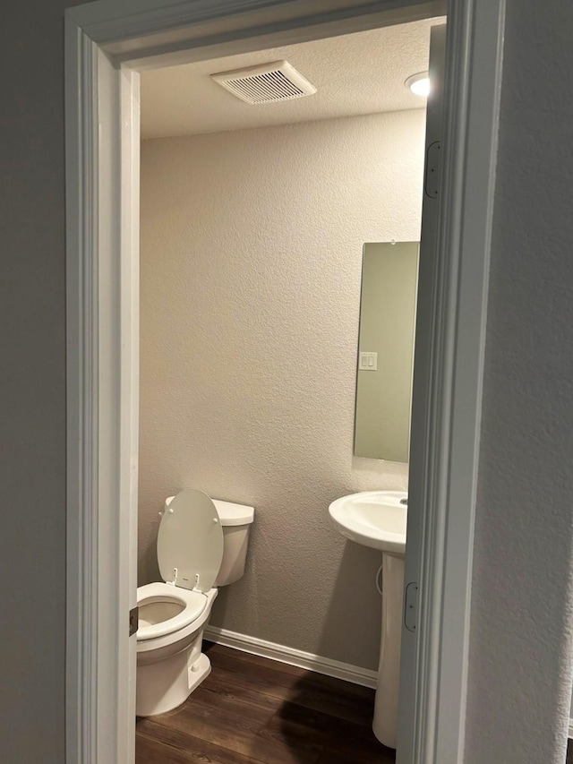 bathroom featuring wood-type flooring and toilet