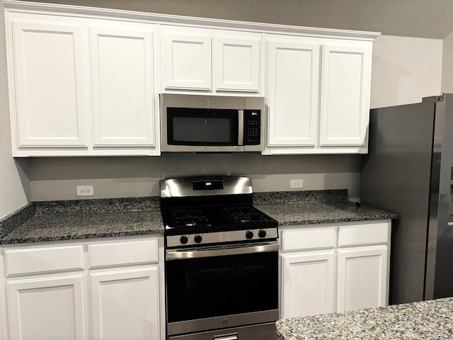 kitchen with dark stone countertops, stainless steel appliances, and white cabinets