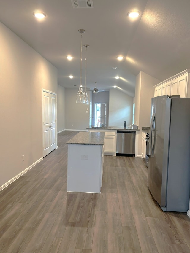 kitchen featuring decorative light fixtures, hardwood / wood-style floors, white cabinetry, and appliances with stainless steel finishes