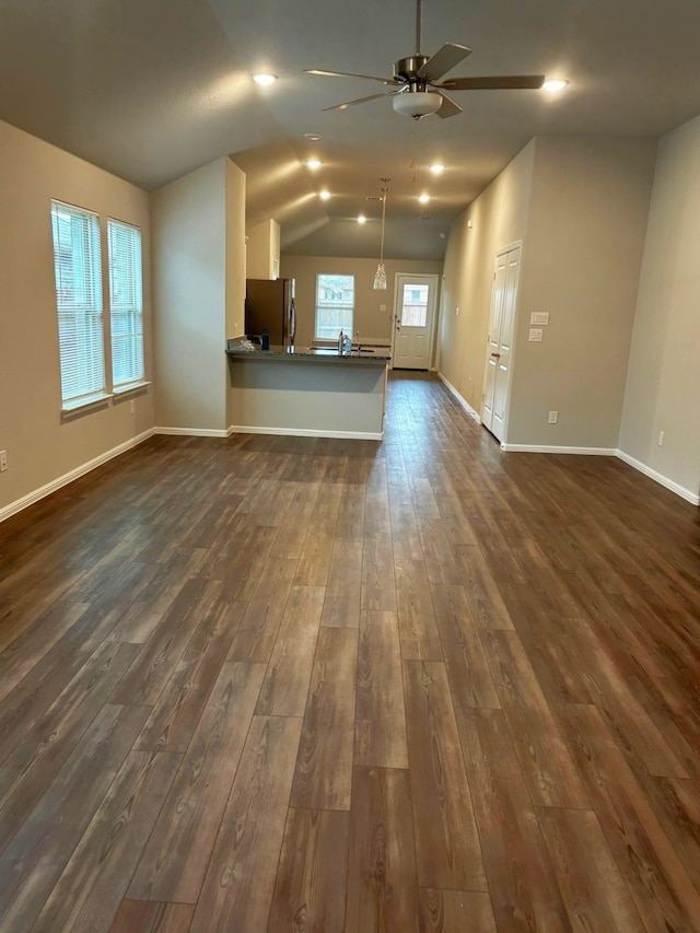 unfurnished living room featuring dark hardwood / wood-style flooring, vaulted ceiling, and ceiling fan