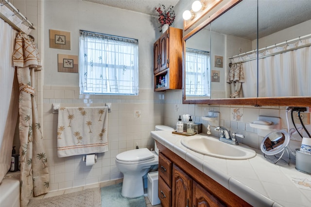 bathroom featuring vanity, tile walls, a textured ceiling, and toilet