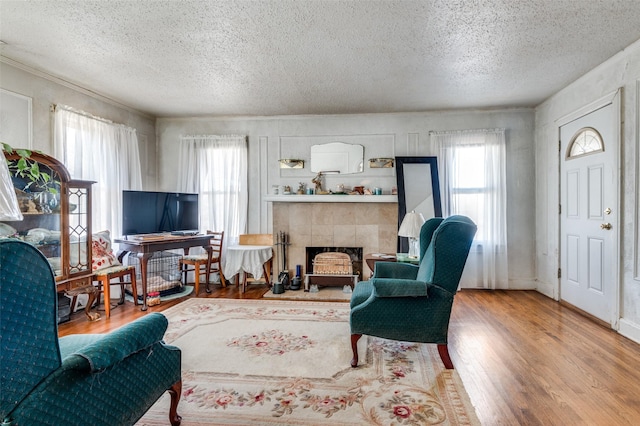 living room with wood-type flooring, a tile fireplace, and a textured ceiling