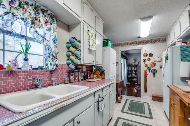 kitchen with sink, white cabinets, and a textured ceiling