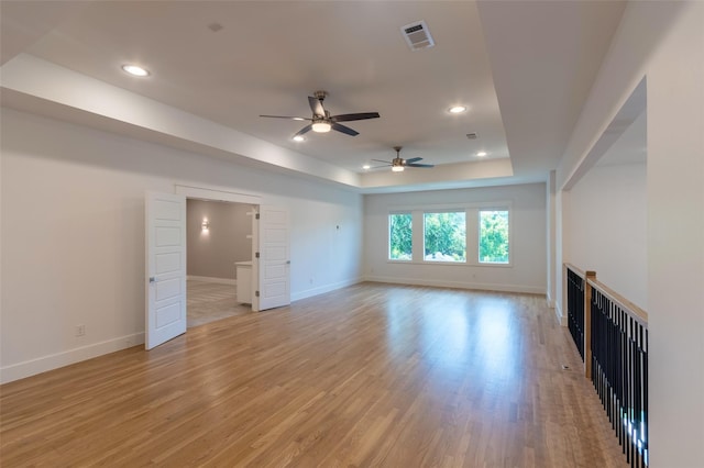 unfurnished living room with a tray ceiling and light hardwood / wood-style flooring