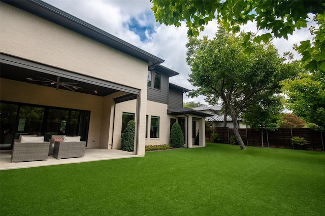 back of house featuring an outdoor living space, ceiling fan, a patio, and a yard