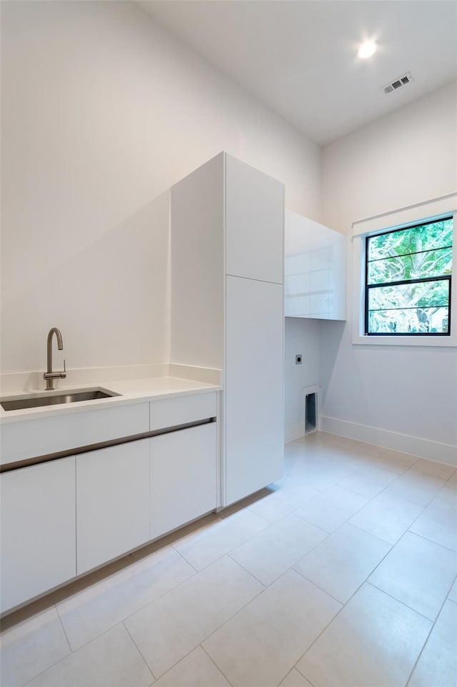 washroom featuring cabinets, light tile patterned floors, and sink