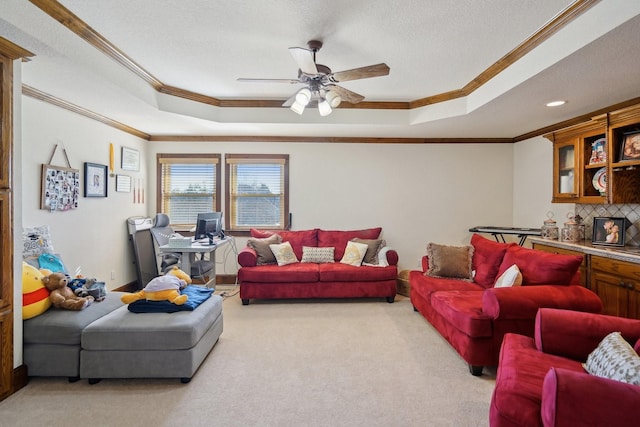 carpeted living room with ceiling fan, a tray ceiling, and ornamental molding