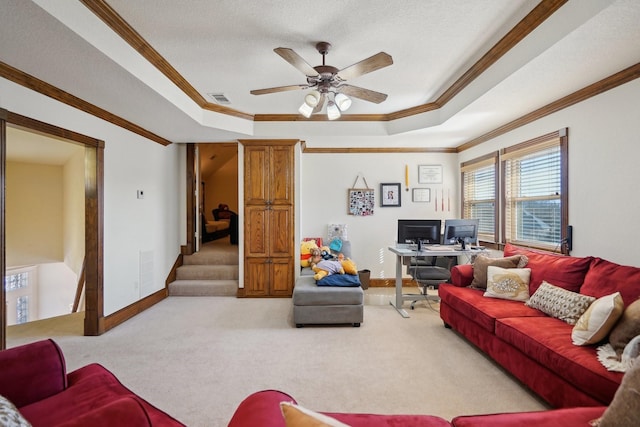 carpeted living room with ceiling fan, ornamental molding, a textured ceiling, and a tray ceiling