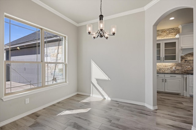 unfurnished dining area featuring light wood-type flooring, ornamental molding, and a healthy amount of sunlight