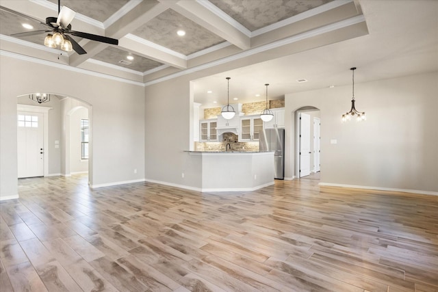 unfurnished living room featuring ceiling fan with notable chandelier, beamed ceiling, light hardwood / wood-style floors, crown molding, and coffered ceiling