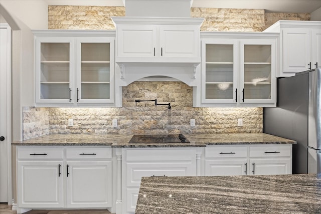 kitchen with white cabinetry, stainless steel fridge, decorative backsplash, and black electric cooktop