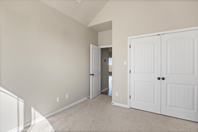 unfurnished bedroom with light carpet, a closet, and vaulted ceiling