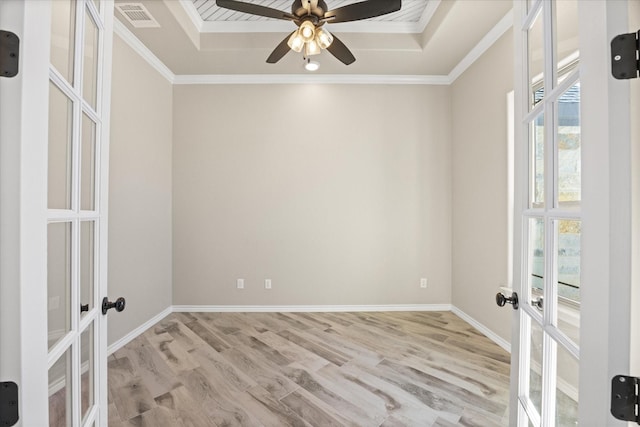 empty room featuring light wood-type flooring, ceiling fan, french doors, and crown molding