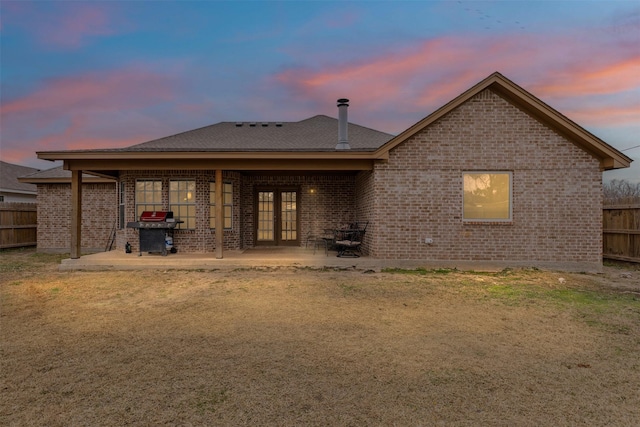 back house at dusk featuring a patio area and a yard